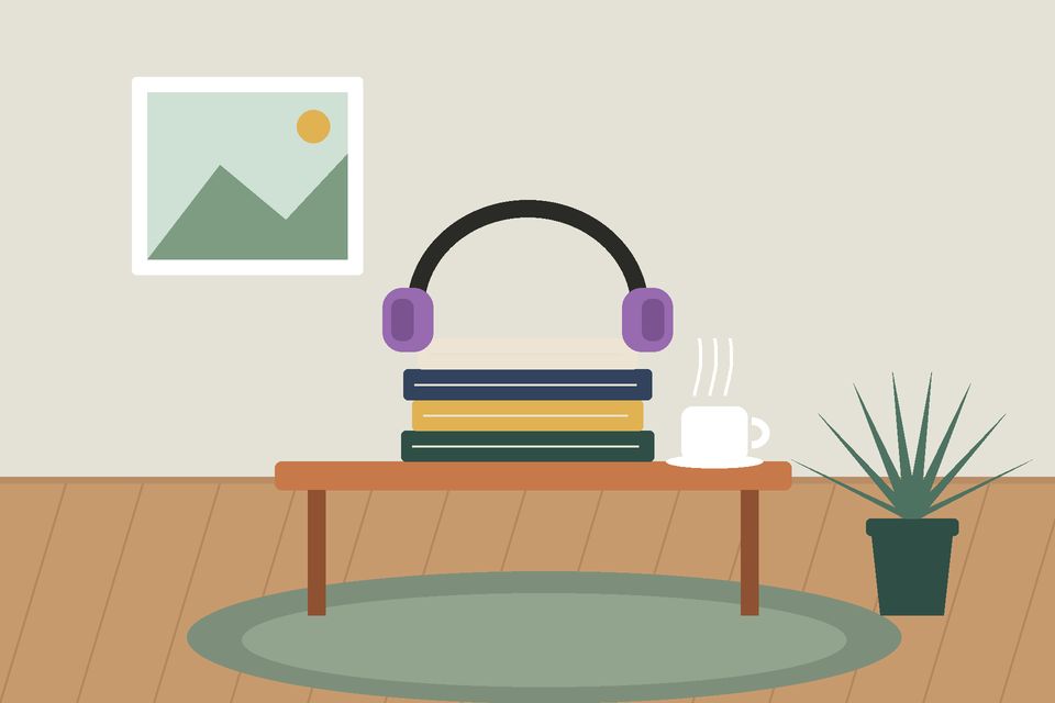 سمّاعتان فوق كتبٍ مكدّسة على طاولةٍ وكوب شاي