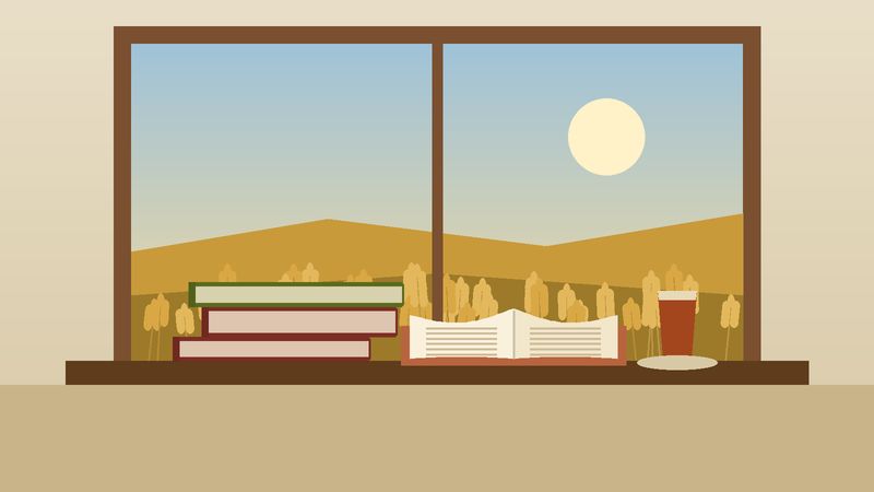 كتبٌ وكوب شايٍ على حافّة نافذةٍ تطلّ على حقل قمح