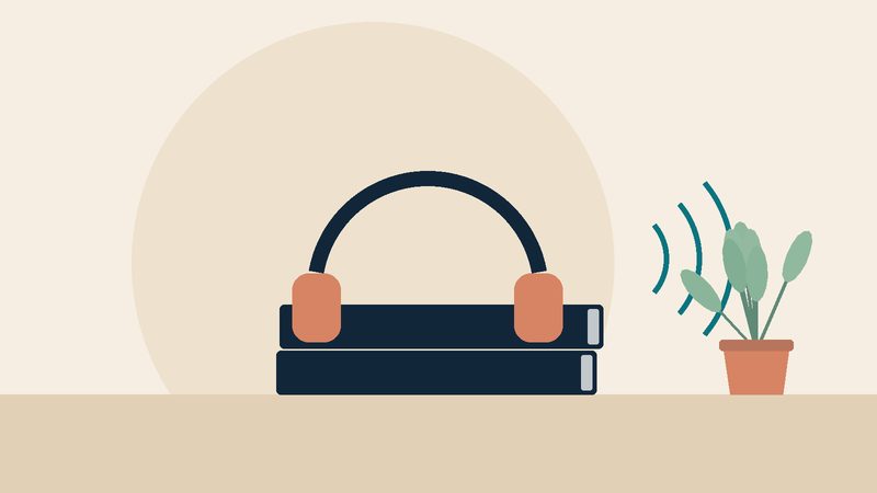 سمّاعتان فوق كتابين مغلقين بجانب نبتة